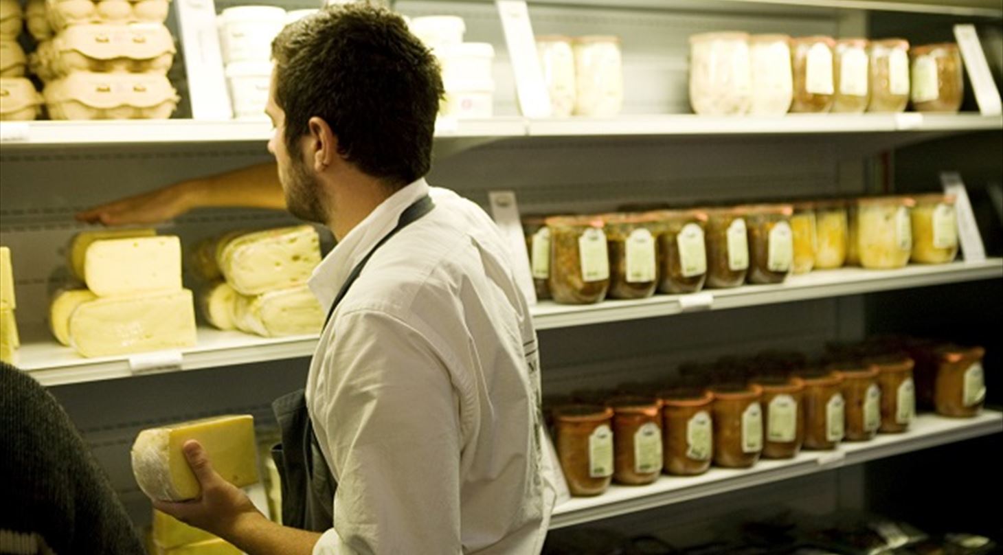 Billedet viser en mand, der er ved at s�tte ost ind i en ostek�ler.